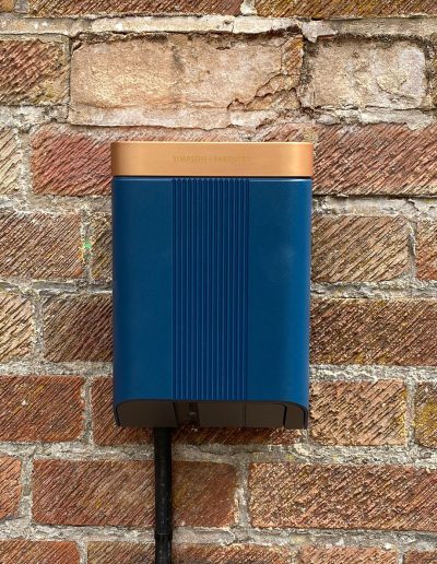 Simpson and Partners charger on a brick wall. The charger is Neptune Blue with a Bronze lid